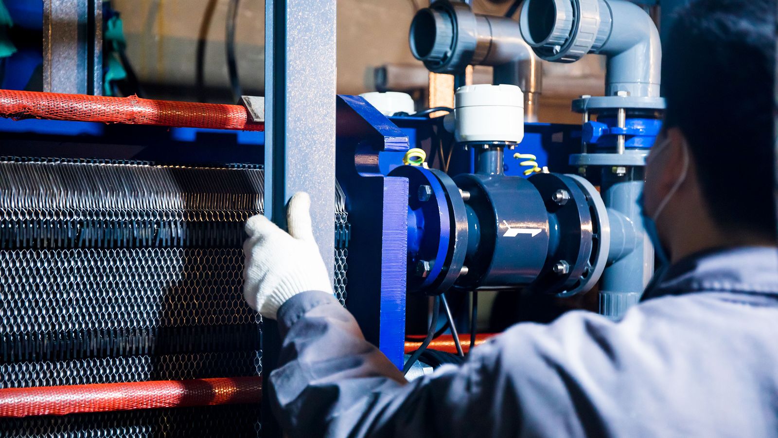 Technician working on industrial piping and mechanical equipment